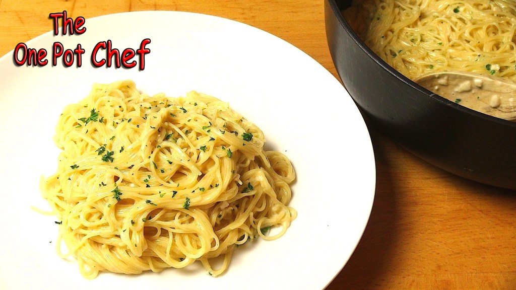 A plate of creamy pasta garnished with parsley, with a pot of more pasta in the background.