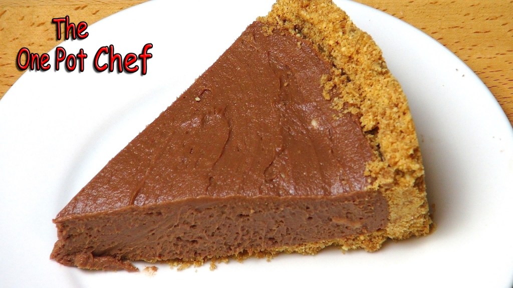A slice of chocolate pie on a white plate, featuring a crumbly biscuit base and a smooth chocolate filling.
