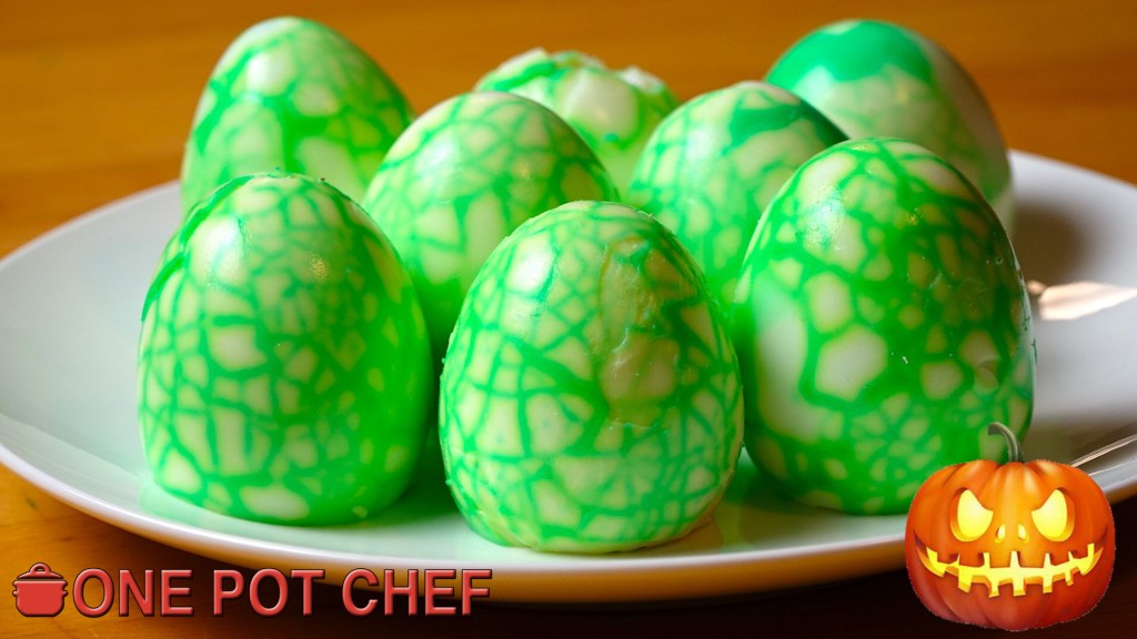 A plate of green marbled chocolate eggs, decorated for Halloween with a vivid design.